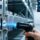 Professional warehouse scene showing UHF RFID metal tags mounted on industrial equipment, handheld RFID scanner in use, clean lighting and modern logistics environment