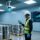 Professional warehouse scene showing RFID-enabled chemical drums, fixed RFID reader antenna, and handheld scanner in use