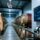 Professional industrial scene showing RFID-enabled wine barrel tracking in a modern winery warehouse with metal shelving, UHF reader antenna, and tagged oak barrels
